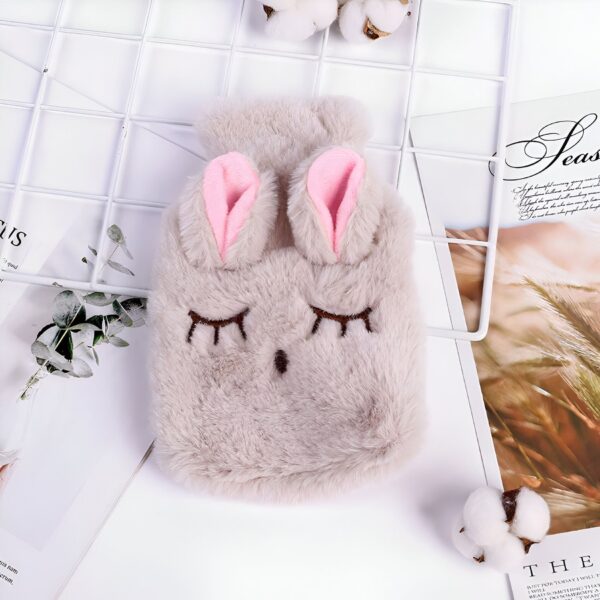 Bouillotte en peluche en forme de lapin avec des oreilles roses et des yeux brodés.