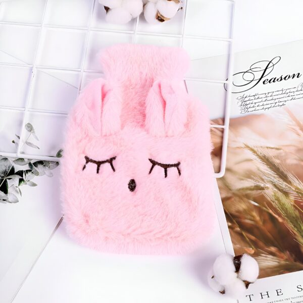 Une bouillotte en forme de lapin rose avec des yeux fermés.