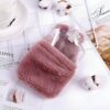 Une bouillotte en plastique transparente recouverte d'une housse en fourrure rose.