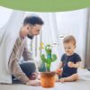 peluche-cactus-chantant-et-dansant-jouet-interactif-7a Un père et son enfant jouent avec un cactus musical interactif. Le cactus chante et danse, et l'enfant est ravi. Le cactus est dans un pot et il a des yeux souriants. Il y a des notes de musique dans l'air. Le cactus est un cadeau parfait pour les enfants.