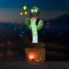 peluche-cactus-chantant-et-dansant-jouet-interactif-9a Cactus en peluche qui danse et chante avec des lumières colorées et un bouton d'enregistrement sur le pot.
