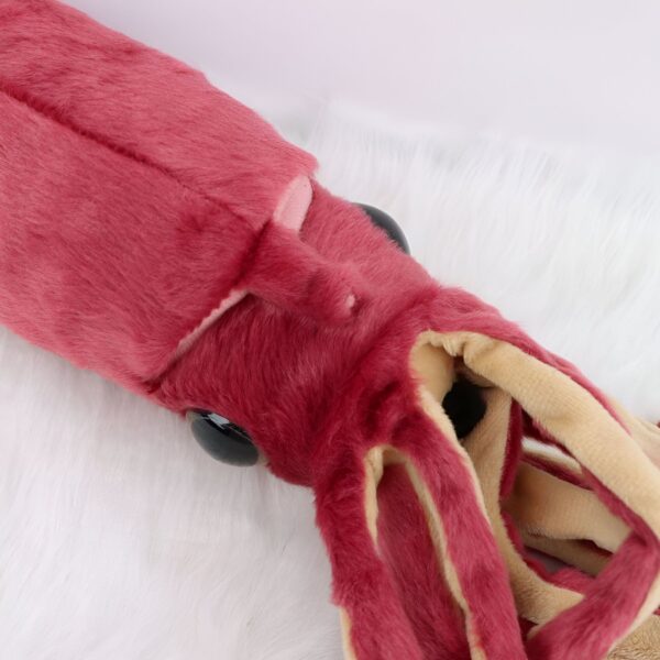 Une peluche de calmar rouge et beige avec de grands yeux noirs.