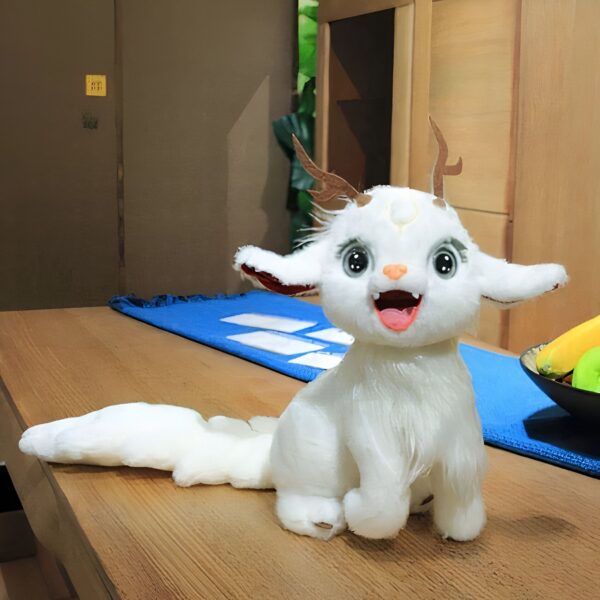 Peluche blanche avec des cornes de cerf, des yeux bleus et une bouche ouverte, sur une table en bois.