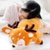 Une jeune femme dort en s'appuyant sur un oreiller en forme de cerf en peluche.