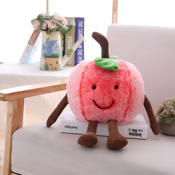 Peluche pomme rouge souriante avec des bras et des jambes en peluche marron assis sur un fauteuil.