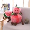 Trois peluches en forme de fruits souriants : une pastèque et deux pommes, assises sur un canapé blanc.