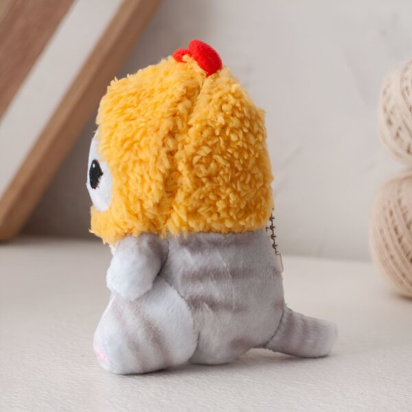 Un adorable petit chat en peluche portant un chapeau jaune et une queue.