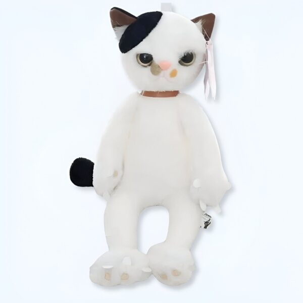 Une peluche de chat blanc avec une tache noire sur l'oeil et une queue noire.