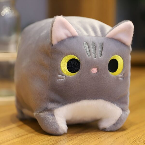 Peluche chat gris avec de grands yeux jaunes et un nez rose.