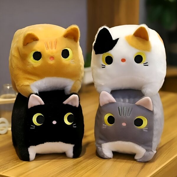 Quatre adorables peluches en forme de chat, orange, blanc, noir et gris, posées sur une table en bois.