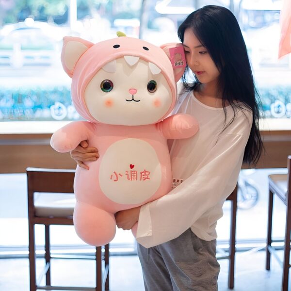 Une jeune femme tient une grande peluche rose en forme de chat avec des yeux bleus et une bouche ouverte. La peluche porte un petit cœur rouge avec l'inscription "小 温柔" (Xiao Wenrou) sur le ventre.