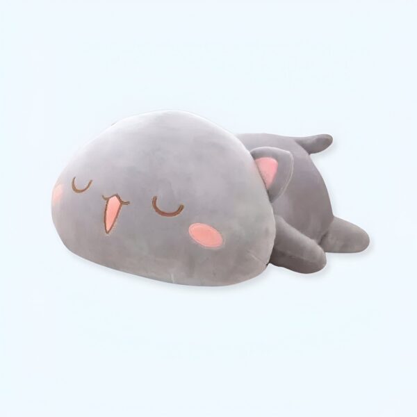 Une peluche grise en forme de chat avec les yeux fermés et un sourire.