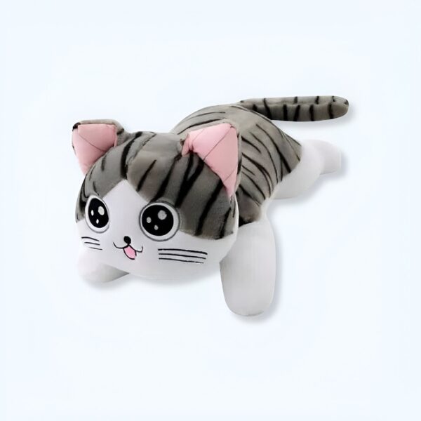 Peluche de chat gris et blanc allongé avec de grands yeux noirs et une langue rose qui sort.