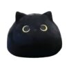 Un coussin en forme de chat noir avec de grands yeux jaunes.