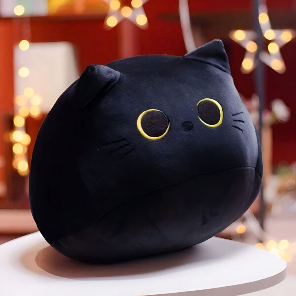 Une peluche noire en forme de chat avec de grands yeux jaunes.