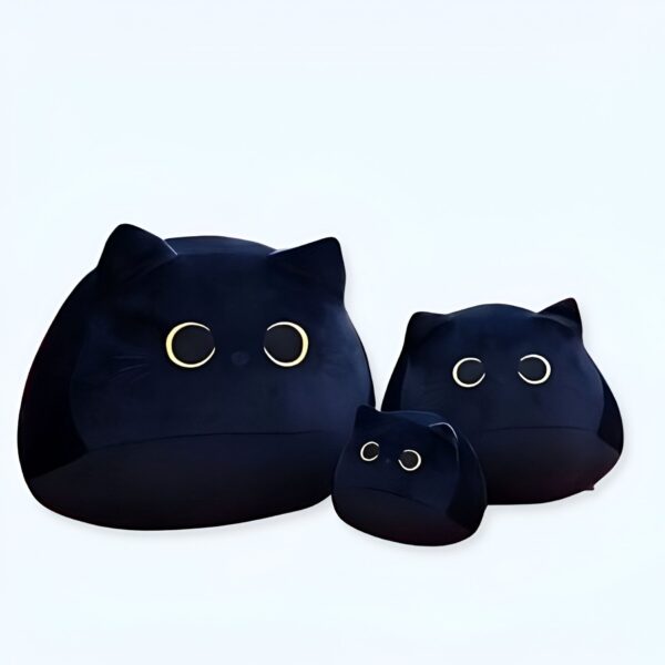 Trois peluches en forme de chat noir avec de grands yeux ronds. La plus grande peluche est au premier plan, les deux autres sont derrière.