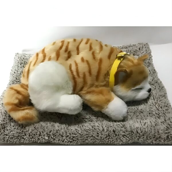 Un chat en peluche orange et blanc portant un collier jaune dort sur un coussin gris.