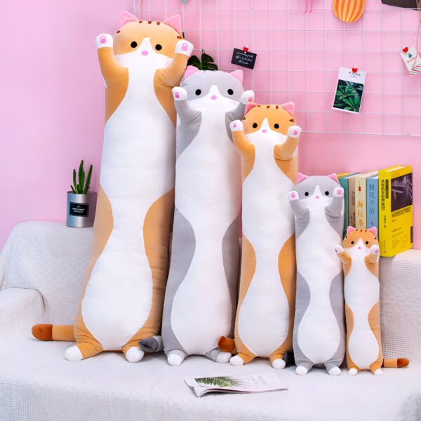 Cinq coussins en forme de chat de différentes tailles, sur un canapé blanc. Les chats sont de couleur orange, blanc et gris. Ils sont disposés du plus grand au plus petit.