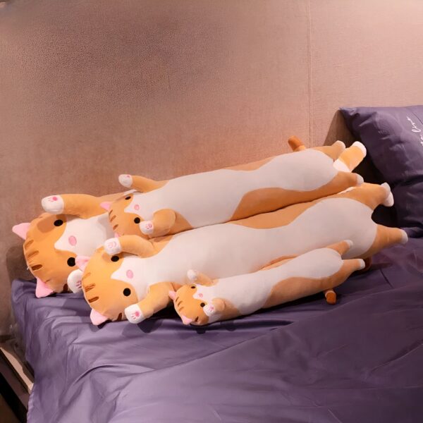 Une collection de quatre coussins en forme de chat orange et blanc sur un lit violet.