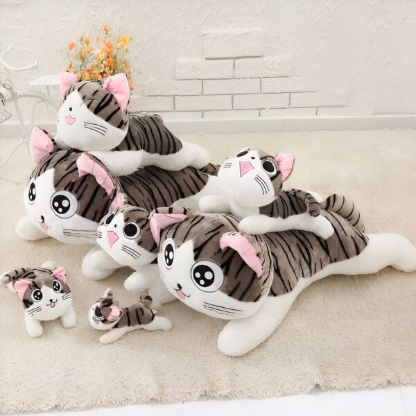 Peluches de chat rayés gris et blancs avec des oreilles roses, différents tailles et formes.