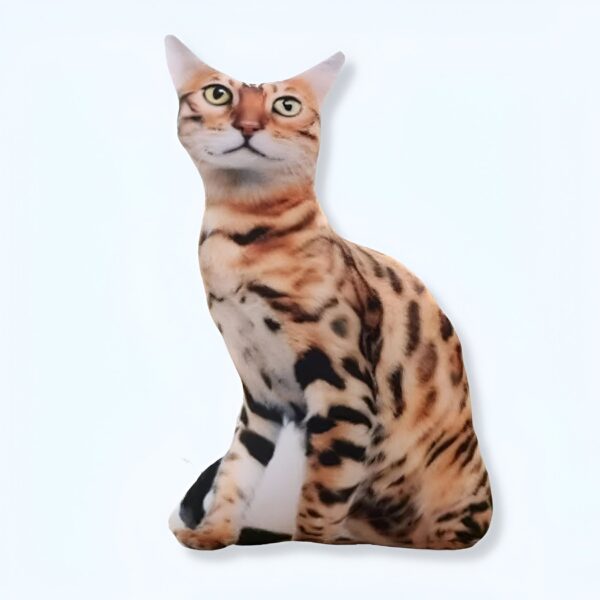 Un coussin en forme de chat tigré assis, regardant vers le haut.