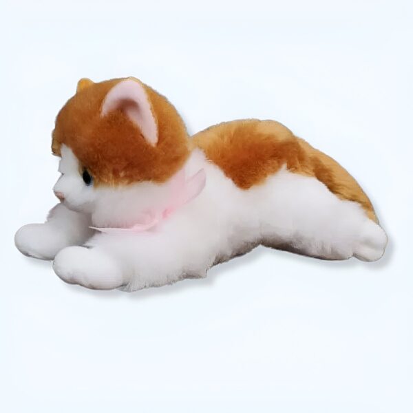 peluche-chaton-marron-1a-2 Un chat en peluche blanc et orange avec un nœud rose allongé sur le ventre.