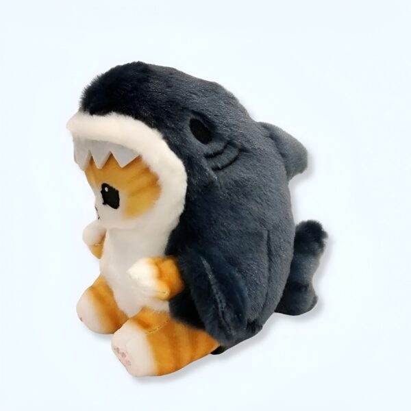 peluche-chaton-requin-pendentif-1a Une peluche de chat orange et blanc portant un costume de requin bleu.