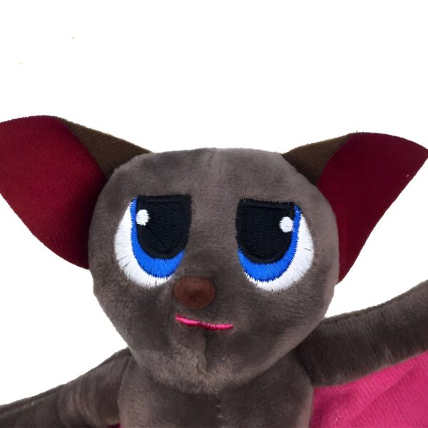 Une peluche de chauve-souris grise avec de grands yeux bleus, des oreilles rouges et une bouche rose.