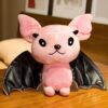 Une peluche rose en forme de chauve-souris avec des ailes noires et une étoile à cinq branches sur la tête.