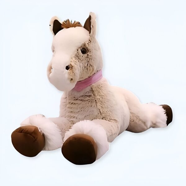Un cheval en peluche beige allongé sur le ventre, avec une crinière brune et un ruban rose autour du cou.