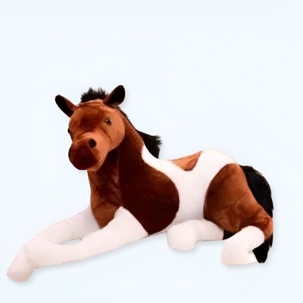 Une peluche de cheval brun et blanc allongée sur le ventre.