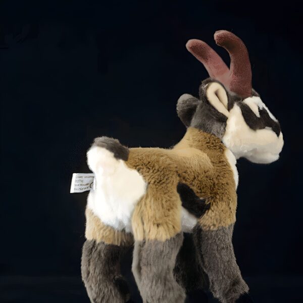 Peluche de chamois debout avec des cornes brunes sur fond noir.