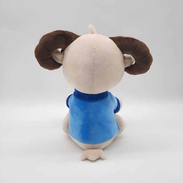 Peluche de bélier en peluche avec des cornes brunes et un t-shirt bleu.