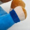 Gros plan sur le poignet d'un jouet en peluche avec un bracelet bleu. La main de la peluche est en fourrure blanche et brune.