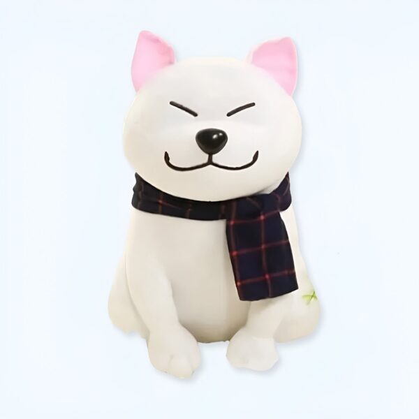 Un chien en peluche blanc assis, avec des oreilles roses et une écharpe à carreaux bleus et rouges.