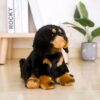Peluche de chien noir et brun assis sur un plancher en bois.