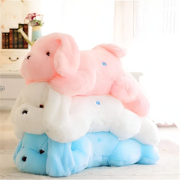 Trois peluches en forme de chiot, rose, blanc et bleu, sont empilées l'une sur l'autre.