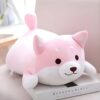 peluche-chien-rose-japonais-peluche-doudou-bebe-jouet-enfant-2a Peluche rose en forme de chien couché sur un livre.