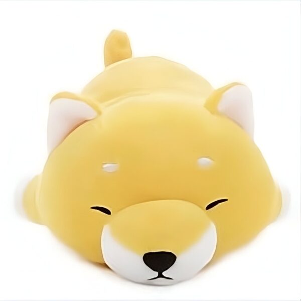 Un petit chien jaune en peluche dormant sur le ventre.