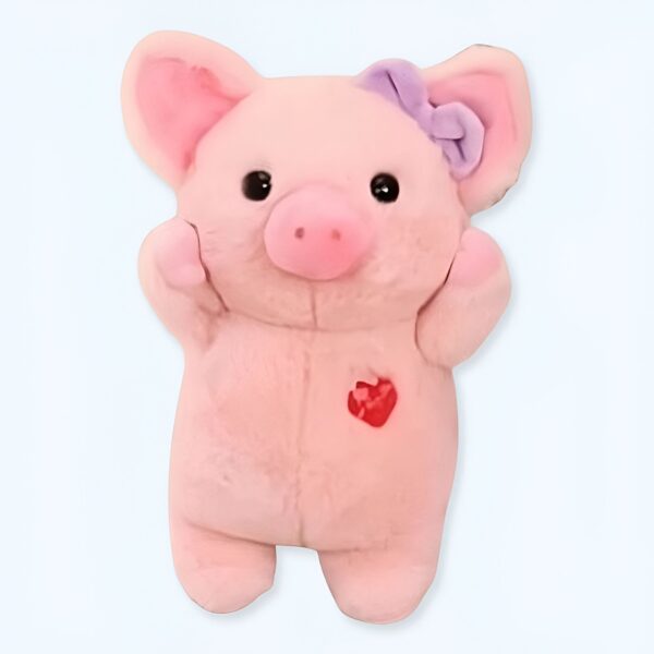 Un cochon en peluche rose avec un nœud violet sur l'oreille et un cœur rouge sur la poitrine.