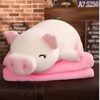 Une peluche blanche en forme de cochon dormant sur un coussin rose.