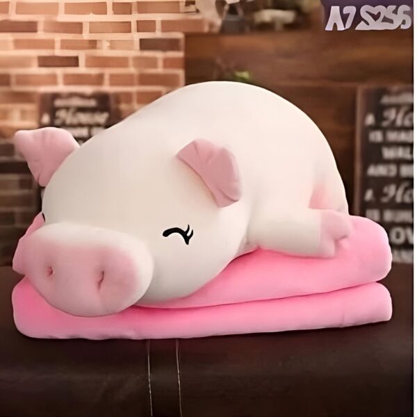 Une peluche blanche en forme de cochon dormant sur un coussin rose.