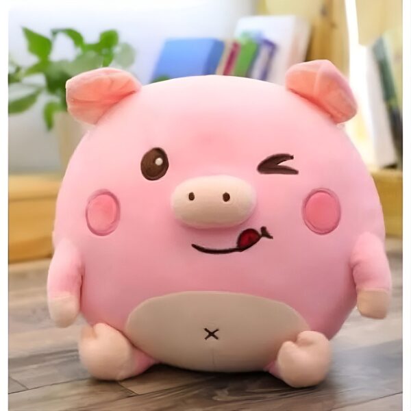 Une peluche rose en forme de cochon avec un sourire espiègle et une langue qui sort. Il a des yeux marrons, un nez rose et des joues rouges.