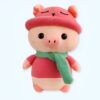 Peluche de cochon rose portant un bonnet et une écharpe vert clair.