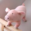 Gros cochon rose en peluche debout sur un banc en bois.