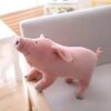 Un gros cochon en peluche rose assis sur un fauteuil blanc.