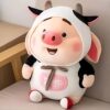 peluche-cochon-kawaii-2a Une peluche rose en forme de cochon souriant, portant un costume de vache blanc et noir avec un nœud brun.