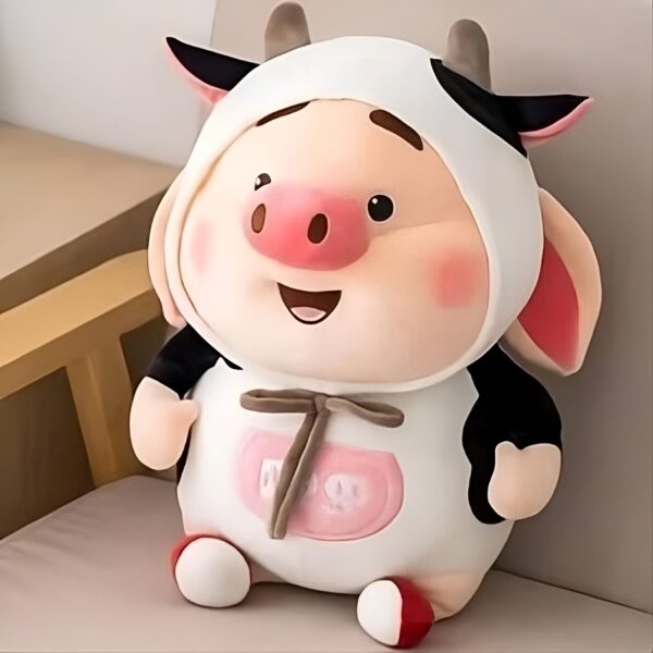 peluche-cochon-kawaii-2a Une peluche rose en forme de cochon souriant, portant un costume de vache blanc et noir avec un nœud brun.
