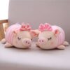 Deux adorables cochons en peluche rose avec des nœuds, couchés sur un canapé blanc.