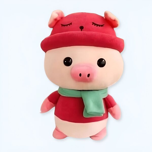 Jolie peluche de cochon portant un chapeau rouge et une écharpe verte.